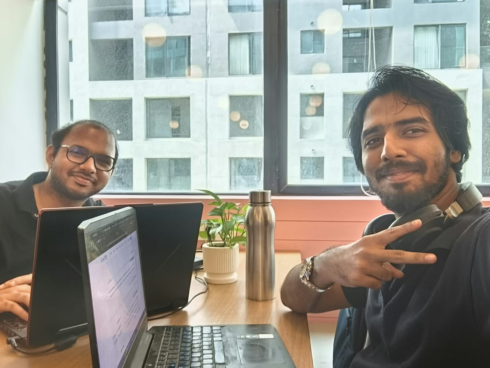Balaji and Saisathish at a desk with two laptops open, building Resse.ai during the hackathon.